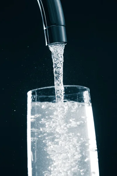 Наливая стакан воды из смесителя крана — стоковое фото