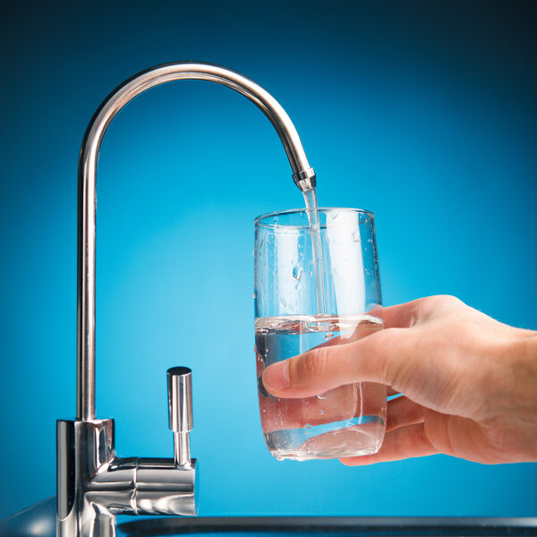 hand pouring a glass of water from filter tap