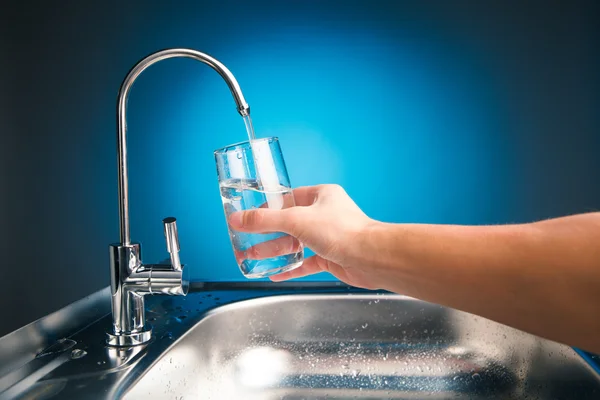 Mano versando un bicchiere d'acqua dal rubinetto del filtro — Foto Stock