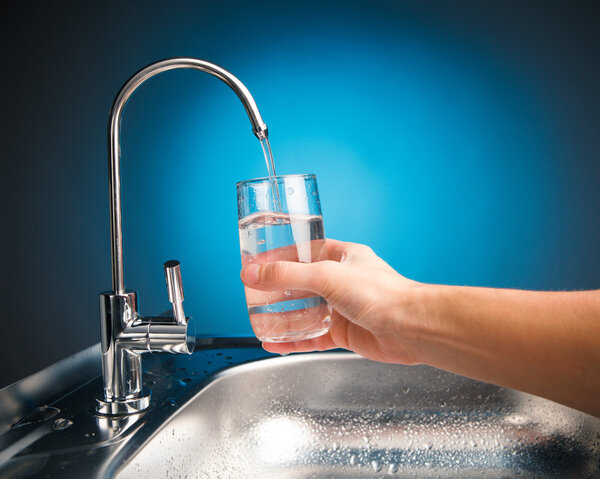 hand pouring a glass of water from filter tap