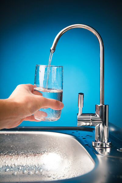 hand pouring a glass of water from filter tap