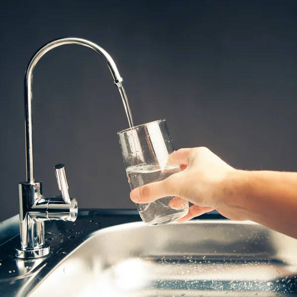 Main verser un verre d'eau du robinet du filtre — Photo