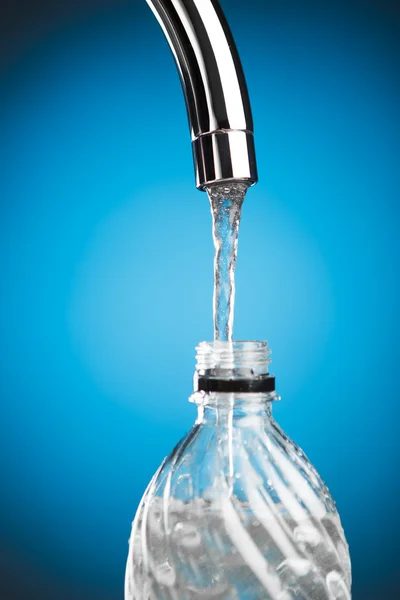 Pouring a bottle of water from mixer tap — Stock Photo, Image