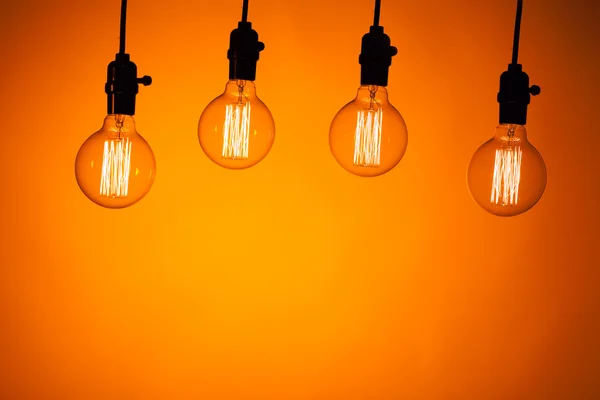 Multitud de lámparas de bombilla sobre fondo naranja — Foto de Stock