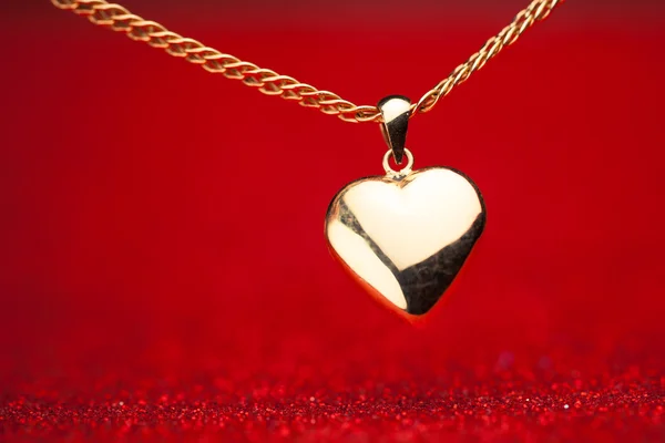 Pendentif coeur or sur fond rouge — Photo