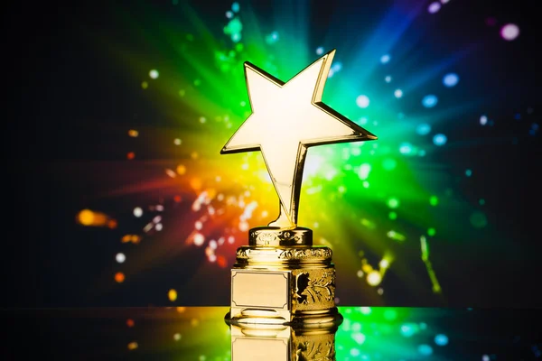Troféu estrela de ouro contra faíscas arco-íris fundo — Fotografia de Stock