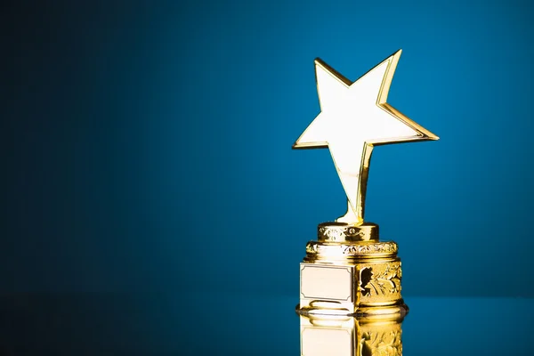 Troféu estrela de ouro contra fundo azul — Fotografia de Stock