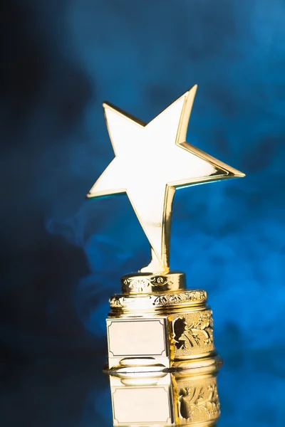 Troféu estrela de ouro contra fundo de fumaça azul — Fotografia de Stock