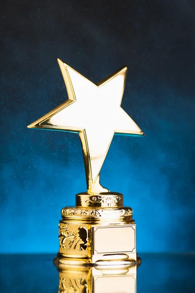 Troféu estrela de ouro contra fundo partículas azuis — Fotografia de Stock