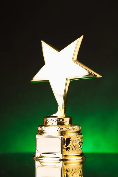 Трофей золотой звезды на фоне зеленой подсветки — стоковое фото