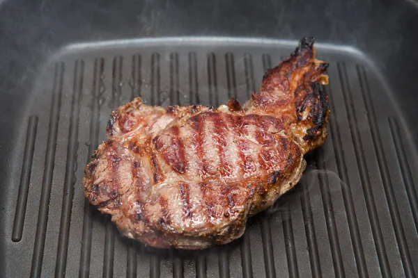 Frying beef steak on a ribbed grill pan — Stock Photo, Image