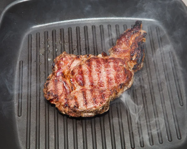 Frying beef steak on a ribbed grill pan — Stock Photo, Image