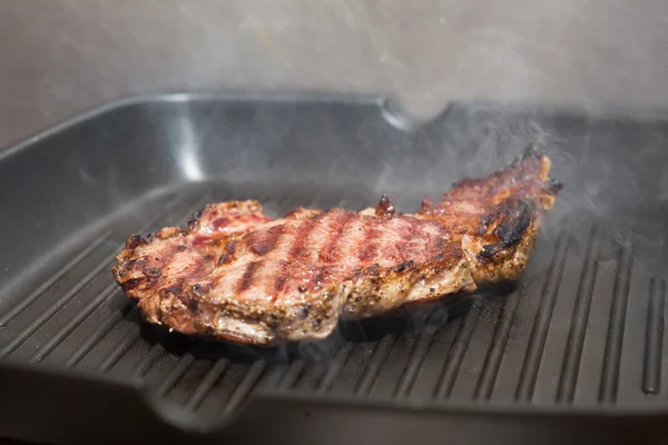 Frying beef steak on a ribbed grill pan — Stock Photo, Image