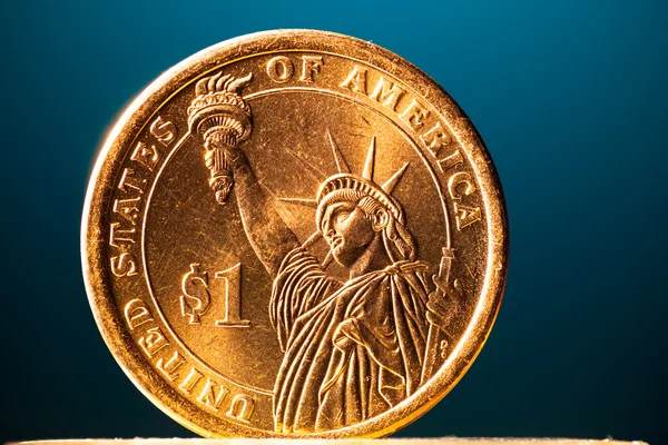 Moeda de dólar dourado no fundo azul, vista macro — Fotografia de Stock