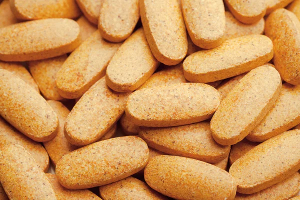 Nutrition supplements, macro view of orange vitamin pills — Stock Photo, Image