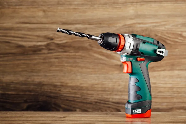 Cordless drill against wooden background — Stock Photo, Image