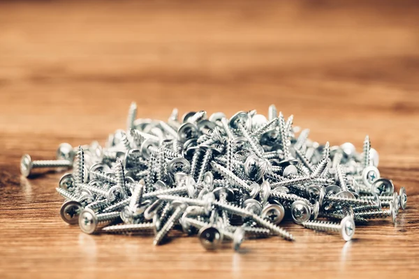 Screws fasteners hardware heap on wooden background — Stock Photo, Image