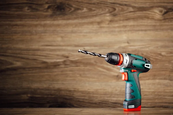 Cordless drill against wooden background — Stock Photo, Image