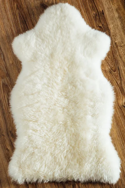 Sheepskin carpet on wooden background — Stock Photo, Image