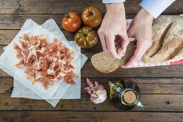 Chef rubbing garlic on a bread slice