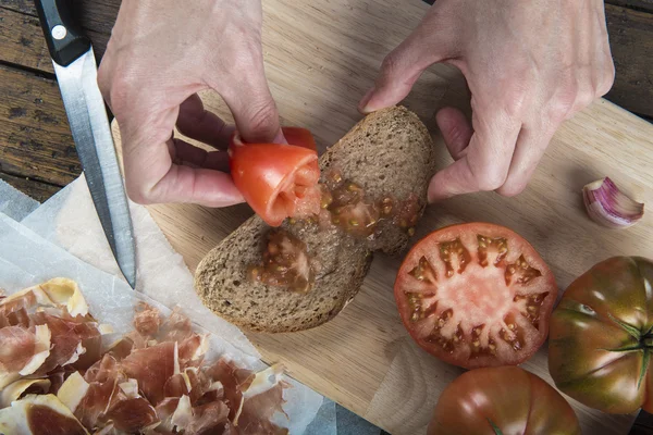 Šéfkuchař třením rajče na chleba — Stock fotografie