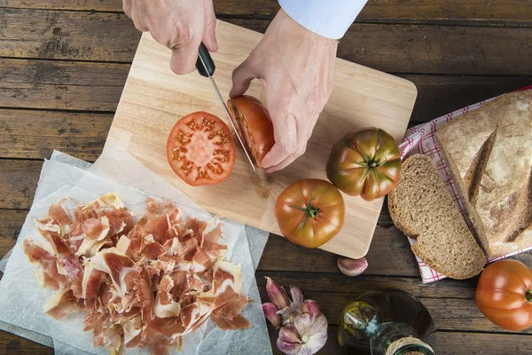 Chef cortando um tomate com uma faca — Fotografia de Stock