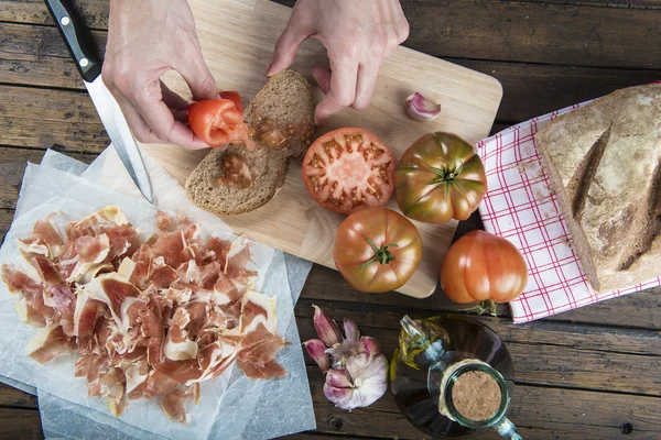 Chef esfregando tomate em uma fatia de pão — Fotografia de Stock