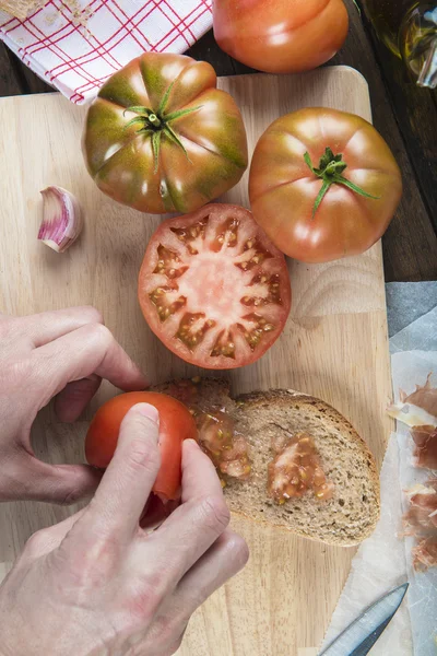 Szef kuchni tarcie pomidor na kromkę chleba — Zdjęcie stockowe