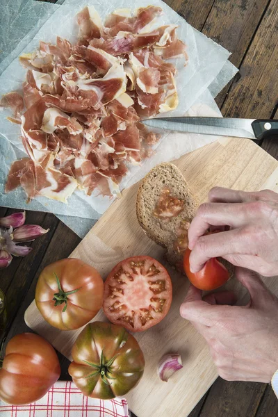 Koch reibt Tomate auf einer Scheibe Brot — Stockfoto