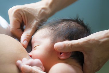 Nurse heps a mother breastfeeding her newborn baby clipart