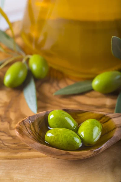 Aceitunas verdes y aceite sobre una cuchara de madera — Foto de Stock