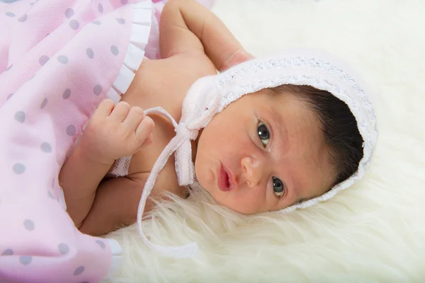 Newborn girl lying happy and relaxed on a white hair blanket — Stock Photo, Image