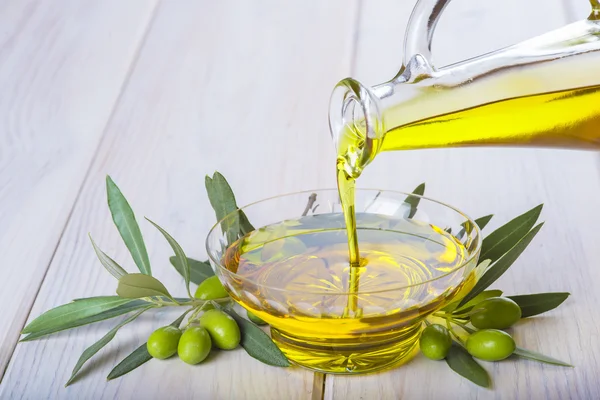 Bottle pouring virgin extra olive oil in a bowl — Stock Photo, Image