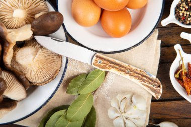 Bir tabak taze deve mantarı ve mutfak masasında yemek pişirmek için malzemeler.