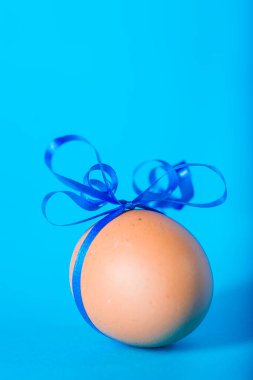 Mavi arka planda bir hediye için dekore edilmiş Paskalya yumurtası.