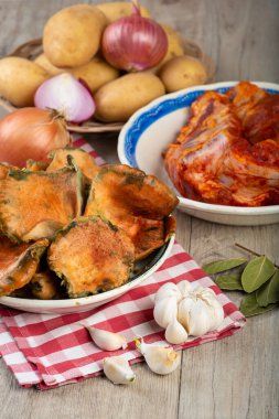 Mutfak masasında patates ve domuz pirzolası bulunan safran süt kapakları.