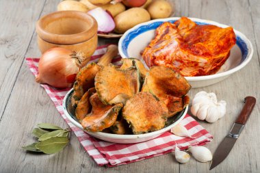 Mutfak masasında patates ve domuz pirzolası bulunan safran süt kapakları.