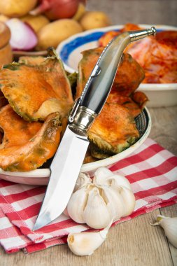 Mutfak masasında patates ve domuz pirzolası bulunan safran süt kapakları.