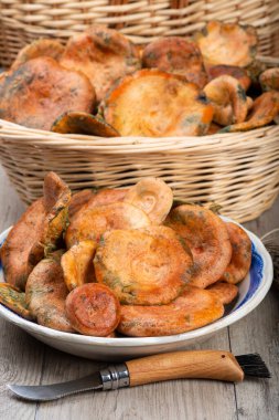 Safran süt kapakları ya da mutfak masasındaki sepet ve kaselerde kırmızı çam mantarları.