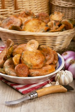 Safran süt kapakları ya da mutfak masasındaki sepet ve kaselerde kırmızı çam mantarları.