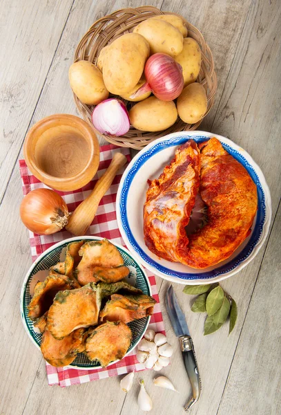 Mutfak masasında patates ve domuz pirzolası bulunan safran süt kapakları.