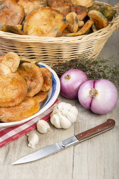 Safran süt kapakları ya da mutfak masasındaki sepet ve kaselerde kırmızı çam mantarları.