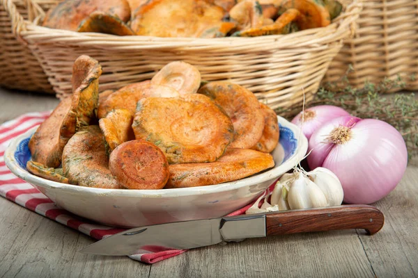 Safran süt kapakları ya da mutfak masasındaki sepet ve kaselerde kırmızı çam mantarları.