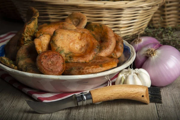 Safran süt kapakları ya da mutfak masasındaki sepet ve kaselerde kırmızı çam mantarları.