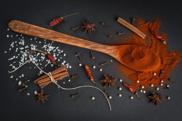 Cuillère en bois avec épices sur fond noir — Photo