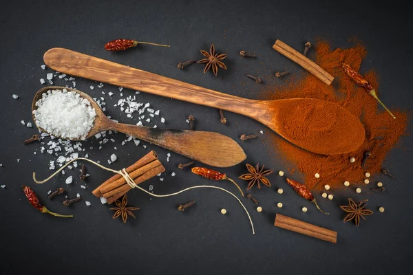 Wooden spoon with spices on a black background — Stock Photo, Image