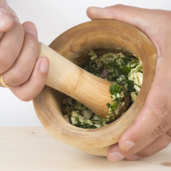 Chef crushing garlic and parsley with mortar and pestle in the k — Stock Photo, Image