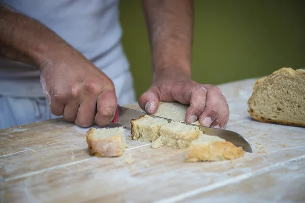 Baker cutting bread on the table — Stock Photo, Image