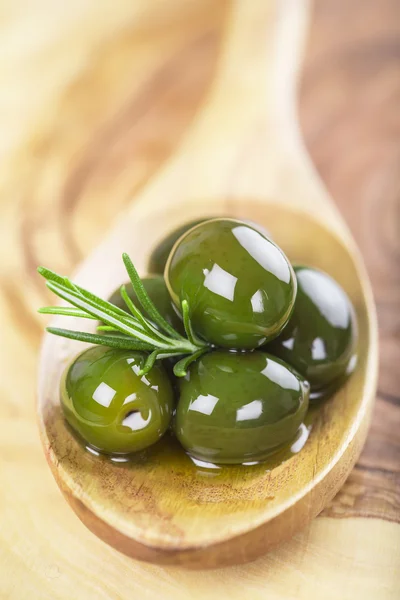 Fechar de azeitonas verdes com o óleo em uma colher de madeira — Fotografia de Stock