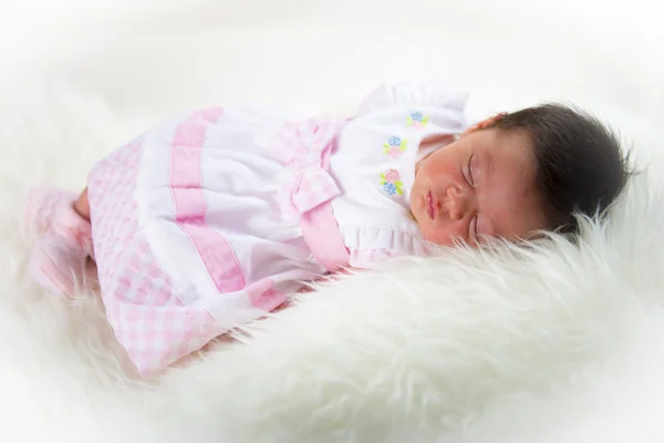 Newborn girl lying happy and relaxed on a white hair blanket — Stock Photo, Image